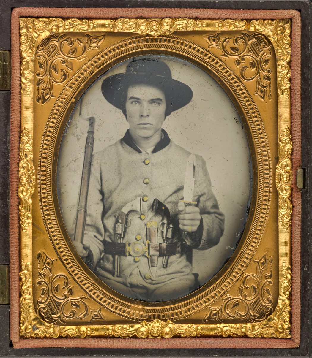 Confederate soldier in uniform wearing a Texas or Mississippi star two-piece belt buckle with two revolvers, side knife, and bayoneted rifle. (Liljenquist Family Collection of Civil War Photographs, Library of Congress)